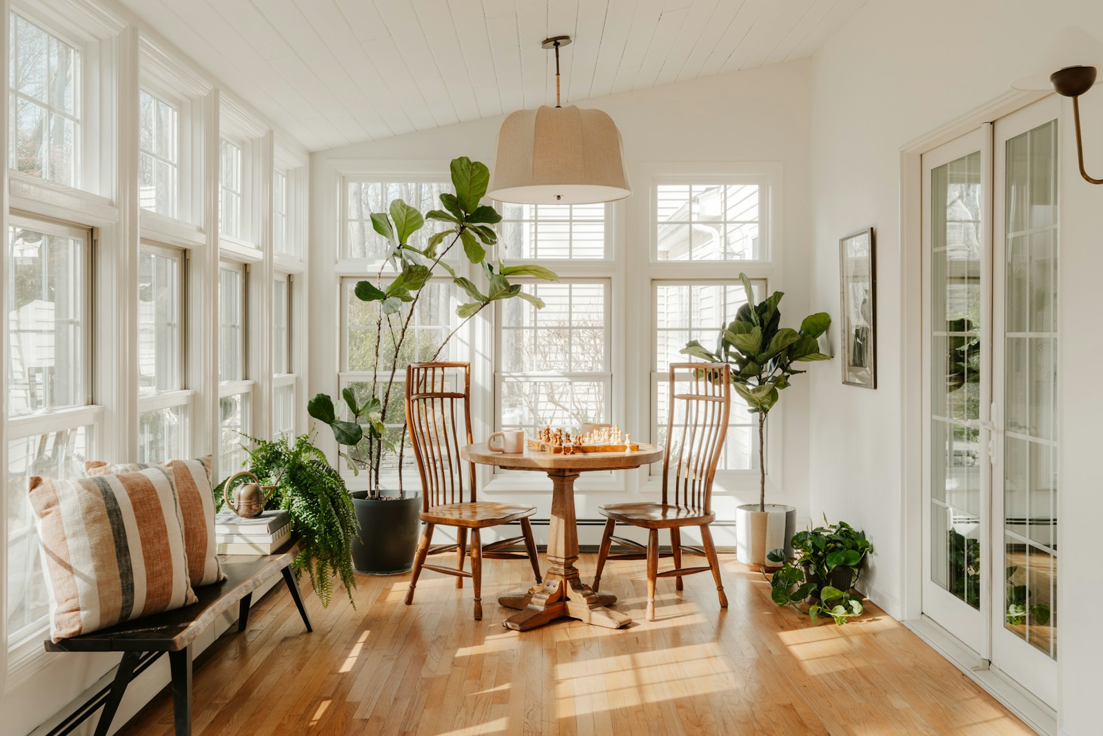 Bright sunroom with plants and dining table.